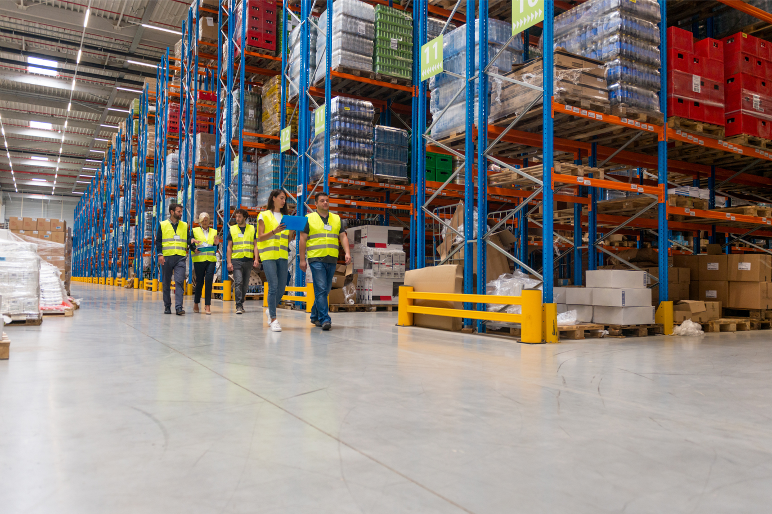 Workers in a warehouse with high shelves and pallets